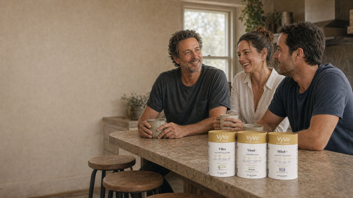 Three people laughing at a kitchen counter with the VyVa supplement canisters